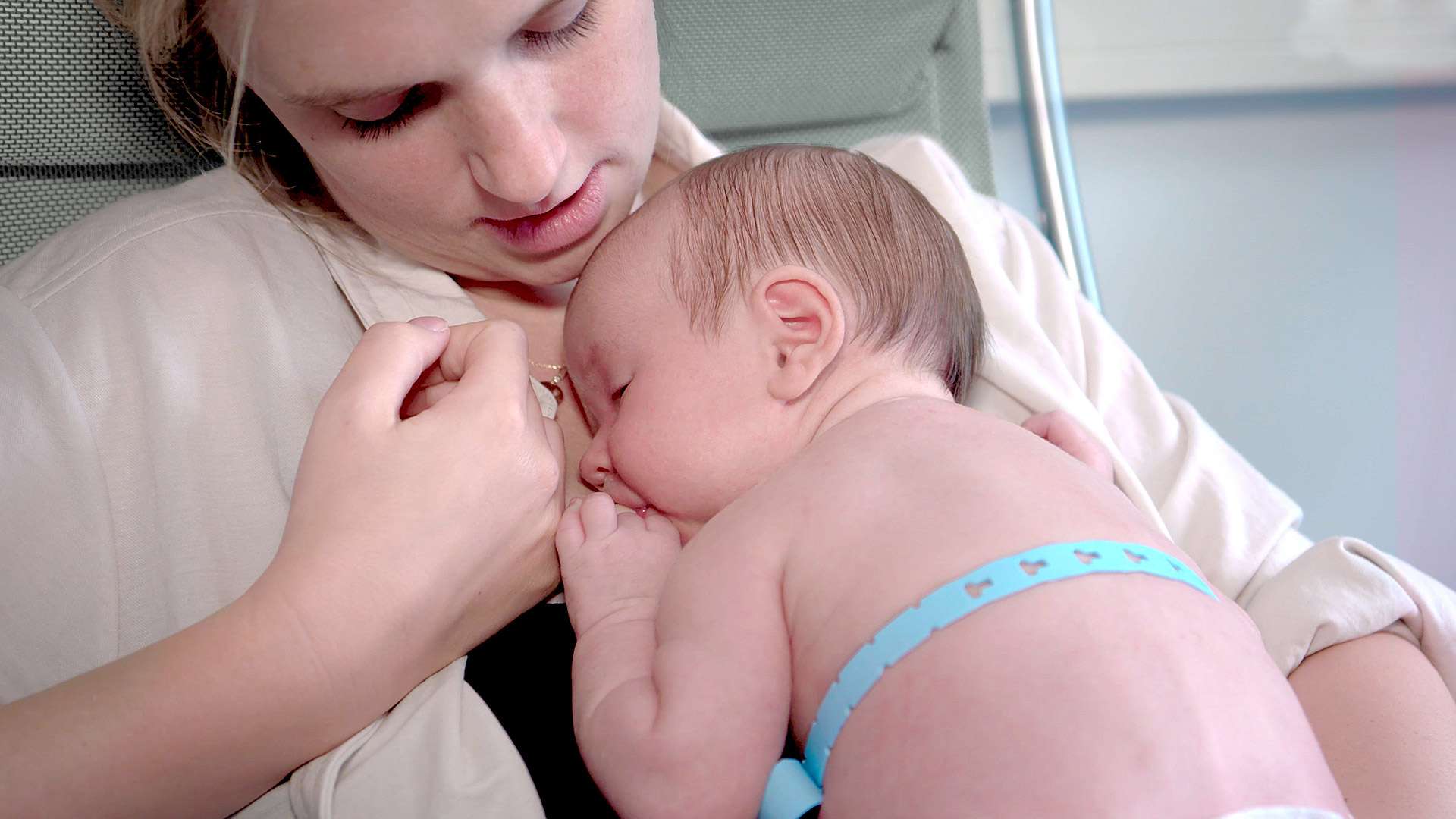 Picture shows a woman with a sleeping baby wearing a blue medical belt
