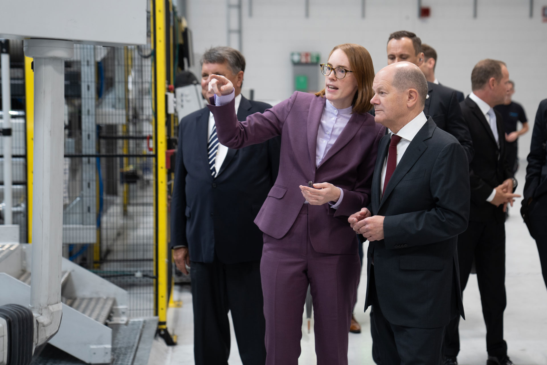 A woman and a man are standing next to each other. The woman points to something to her left that is not in the picture