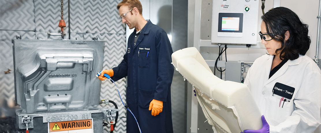 Two employees in protective clothing operating technical equipment and testing components in a laboratory or production environment