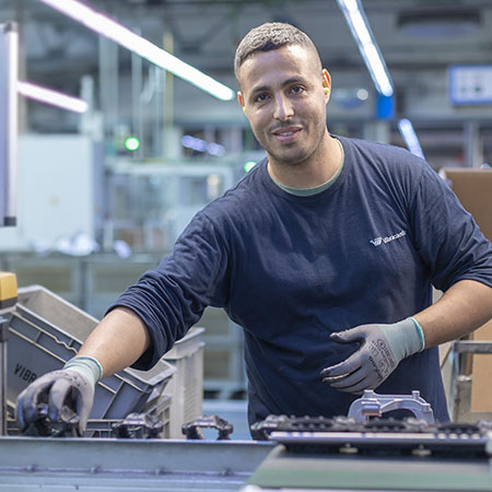 Photo shows a production employee looking into the camera