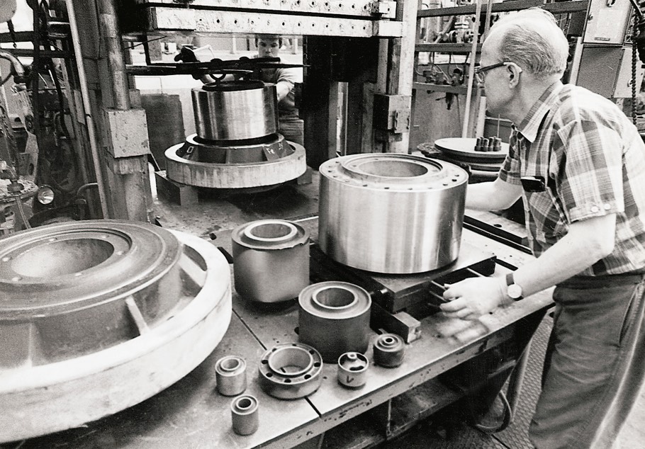 The picture shows an elderly man working on a machine that produces vibration control ultra bushings