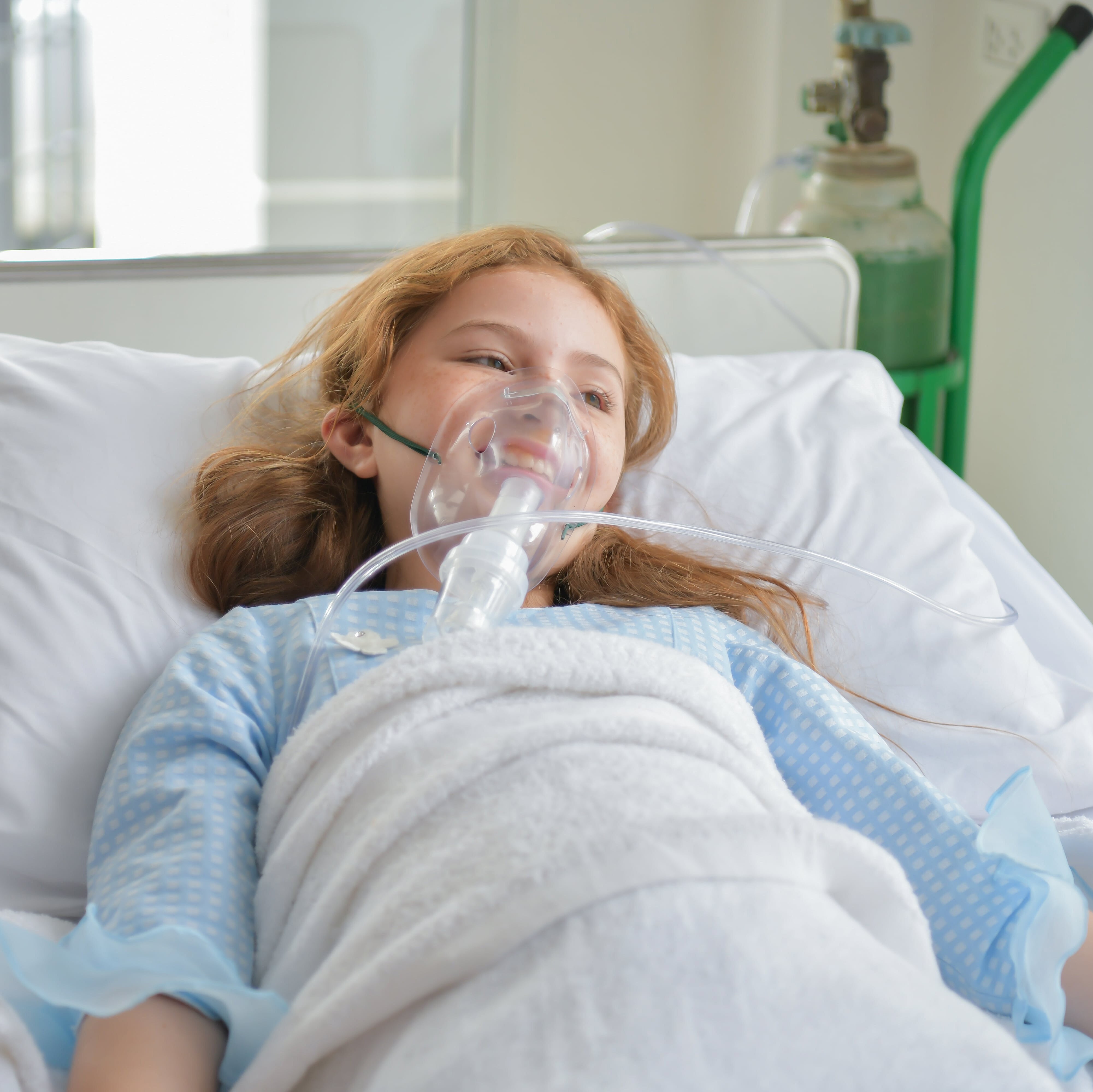 a girl in a hospital bed with an oxygen mask