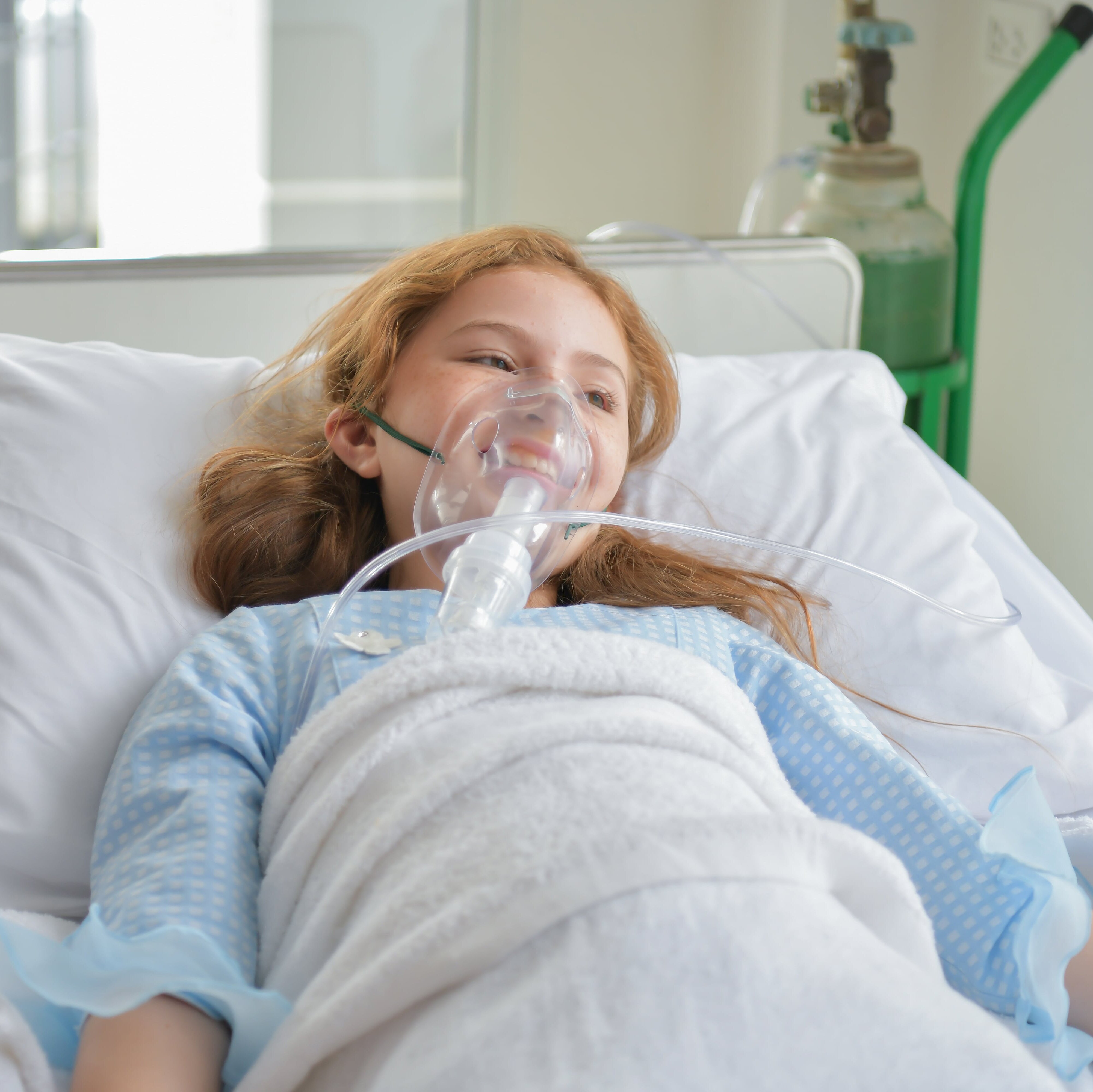 a girl in a hospital bed with an oxygen mask