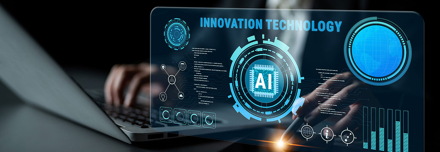 Detail of laptop and mouse pen. Above it is a virtual screen with diagrams and references to the integration of AI in development and processes.