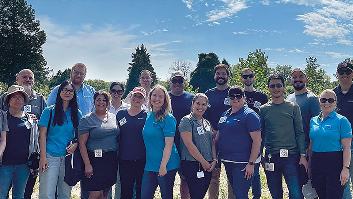 Eine Gruppe von Menschen, die nebeneinander stehen und in die Kamera lächeln