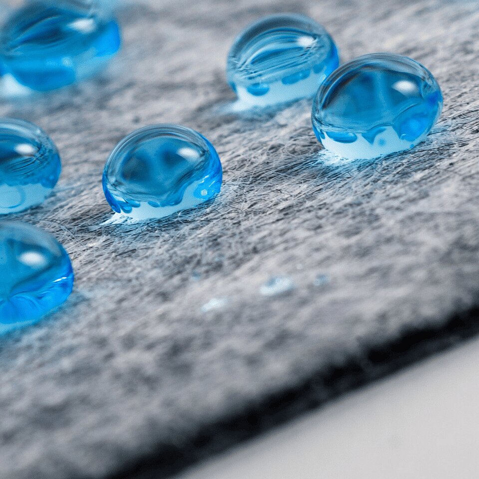 Drops of a blue liquid on a gray non-woven