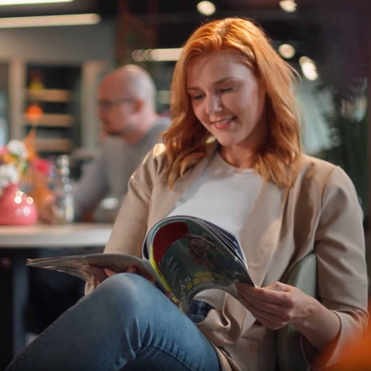 Eine junge Frau sitzt im Cafè und liest in einem Magazin