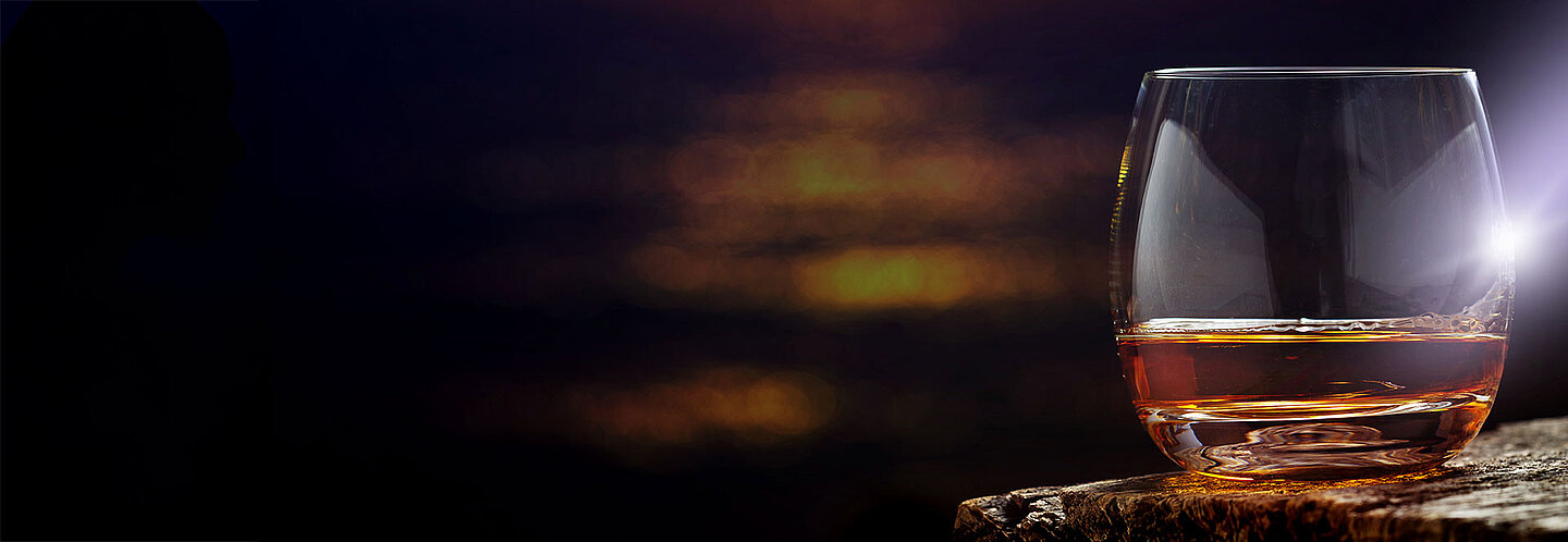 A glass of whiskey against a dark background