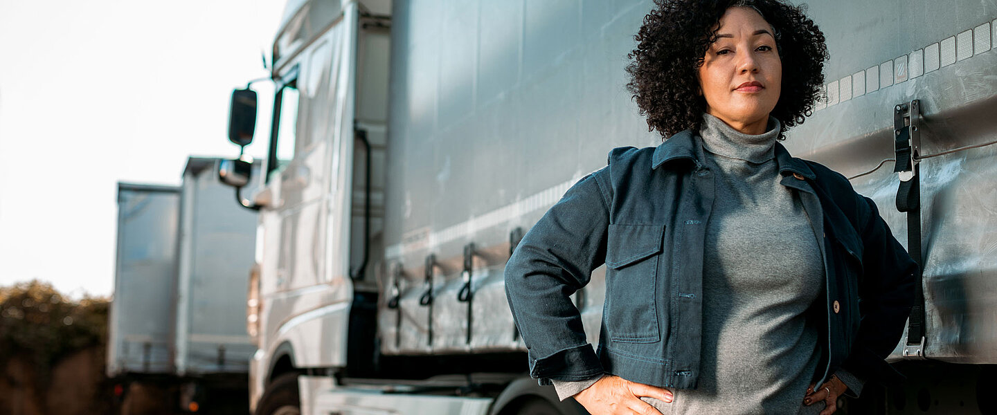 Women with dark curly hair standing in front of a truck.