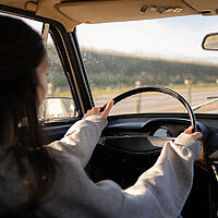 Eine Frau von hinten, die ein Auto fährt